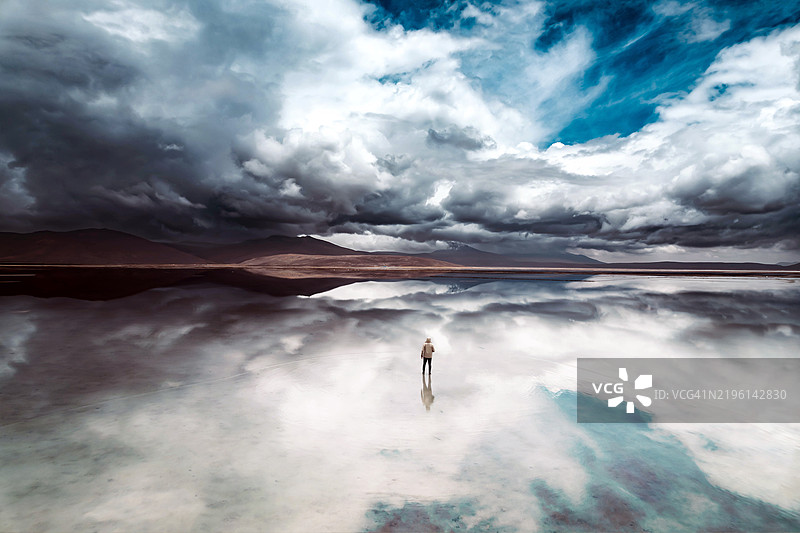 梦幻般的时刻，走在天空之上，映照在盐滩的水面上图片素材