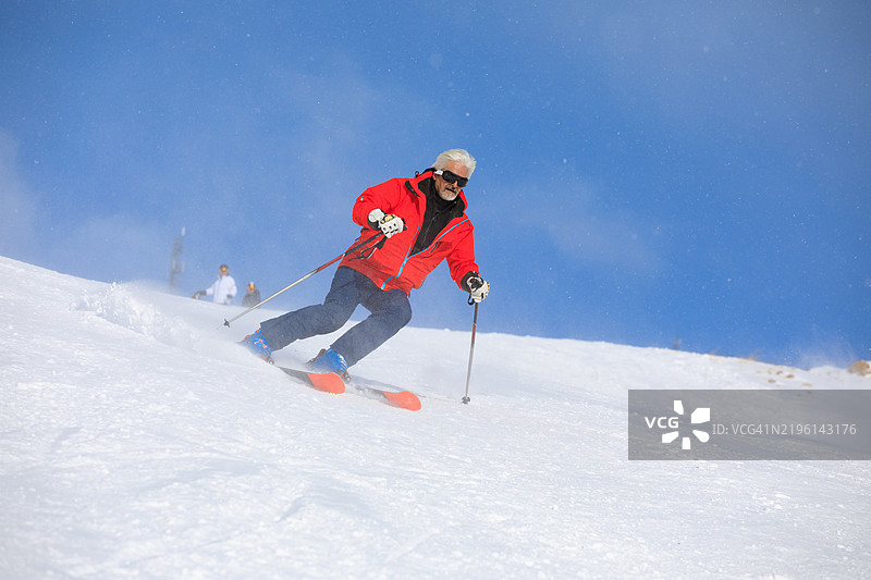 滑雪冬季运动。充满活力的男性滑雪者在阳光明媚的滑雪度假村享受滑雪乐趣,周围是飘雪的环境。欧洲阿尔卑斯山的雪山,滑雪区域为瓦尔迪泽尔 - 蒂涅。图片素材