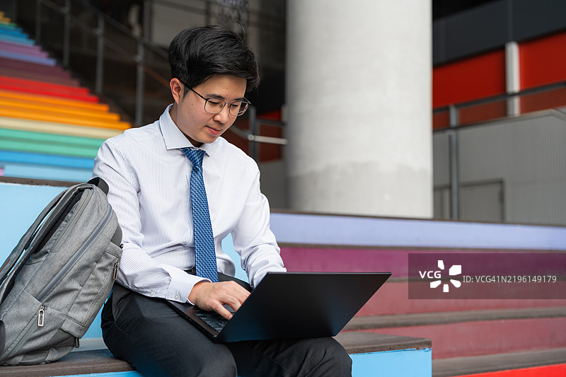 亚洲商人在现代城市户外使用笔记本电脑工作图片素材