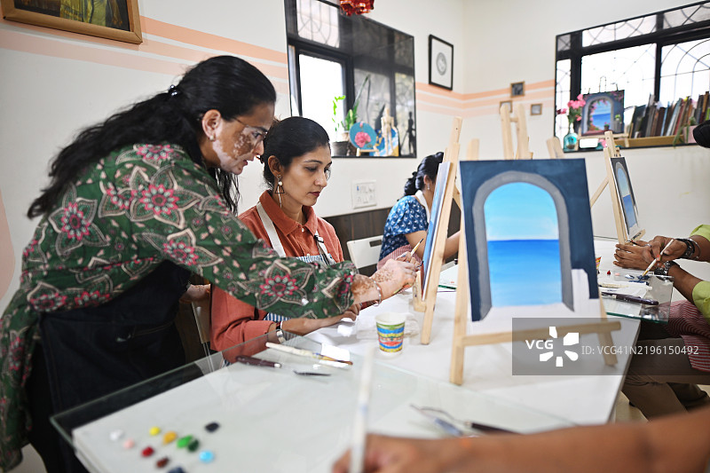 熟练的工匠在创意工作室中热情地教授画布绘画。图片素材