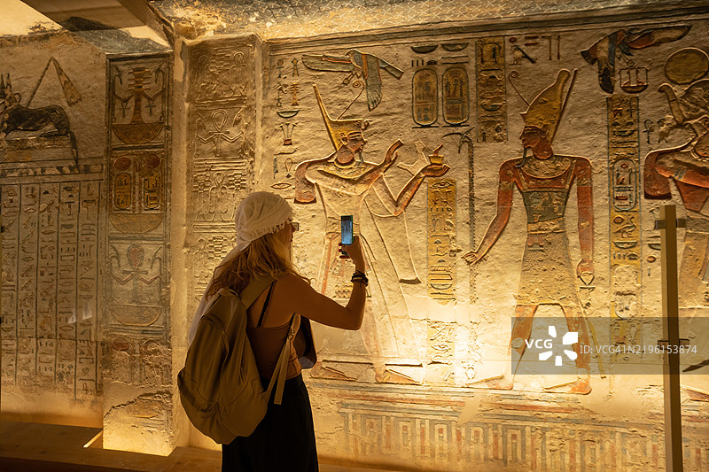 女性在埃及卢克索的国王谷拉美西斯九世墓（KV6）内的房间参观时使用智能手机拍照。图片素材