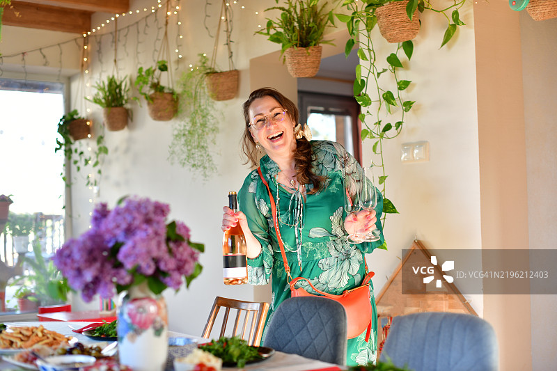 微笑的女性在家聚会上喝酒并看着镜头图片素材
