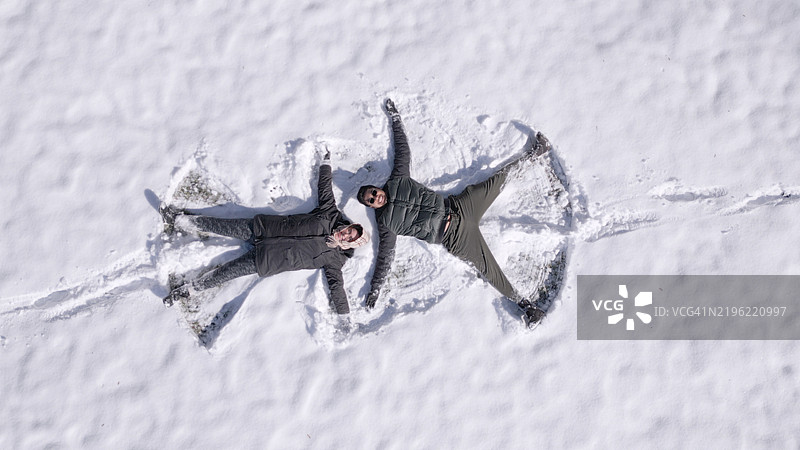 情侣在雪地里做雪天使 - 俯视图图片素材