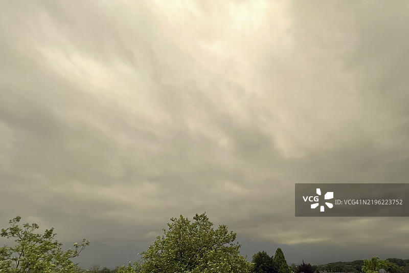 春季德国欧洲的雷暴前方，树梢下方的阴云雨层和阴沉的天空图片素材