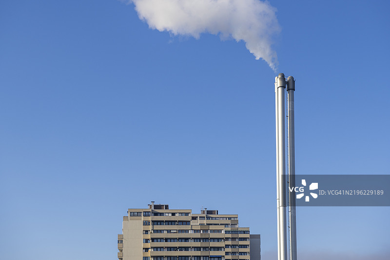 清澈天空下的烟囱冒烟，建筑的上层可见，住宅楼，热电联产厂，区域供热，维嫩登，巴登-符腾堡州，德国，欧洲图片素材