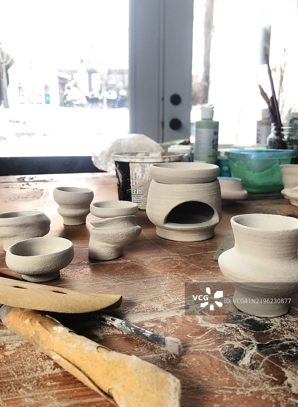 许多正在制作中的自制陶土杯放在魁北克加拿大的木桌上，冬季时节。图片素材