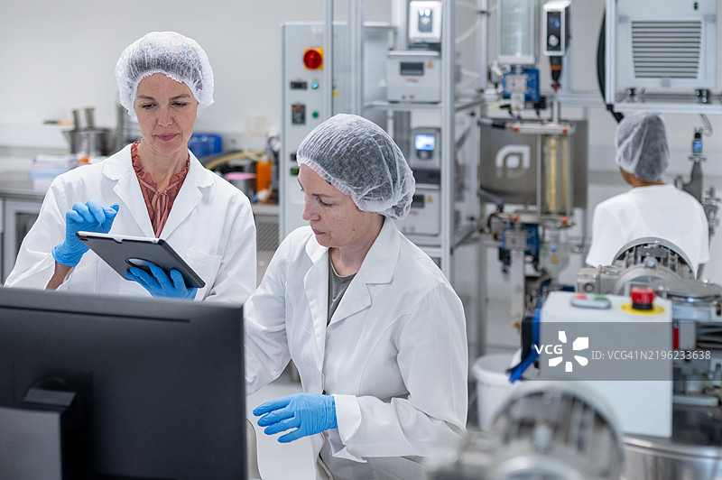 两名女性药剂师在制药实验室中使用平板电脑进行化妆品生产图片素材