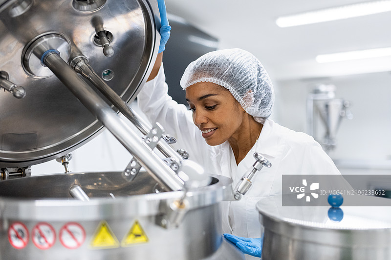 一位拉丁裔女性药品生产工人在工作场所摆姿势。图片素材