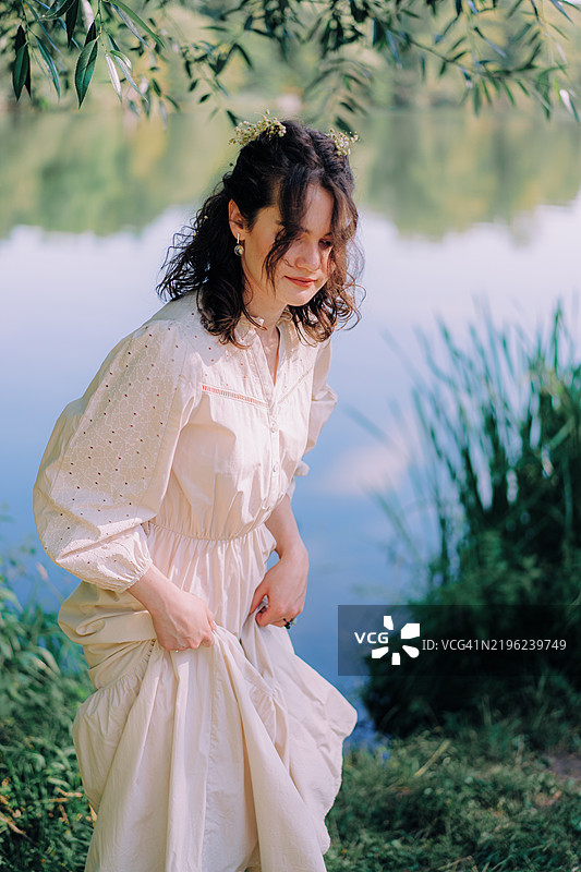 年轻女性在阳光和树影下享受大自然。春天。图片素材