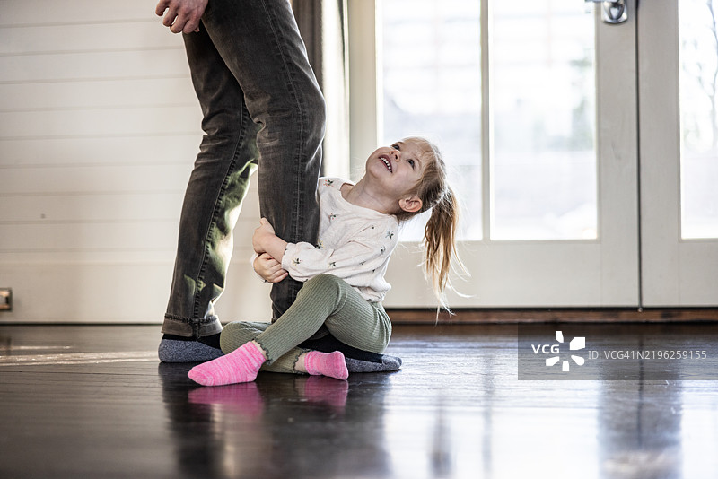 小女孩抓着爸爸的腿图片素材