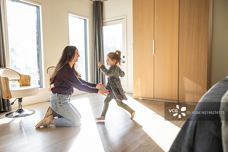 小女孩在阳光明媚的房间里朝母亲跑去图片素材