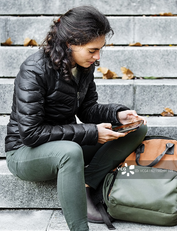 城市中坐在台阶上使用手机的女性图片素材