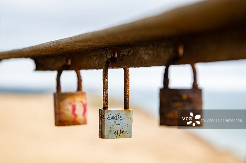 挂在丹麦鲁布耶格灯塔生锈的横梁上的挂锁，位于洛肯和伦斯特鲁普之间的北海沿岸图片素材
