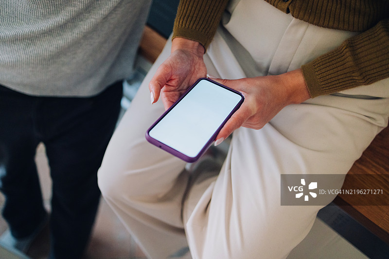 特写镜头：一个人手持一部白色空白屏幕的智能手机图片素材