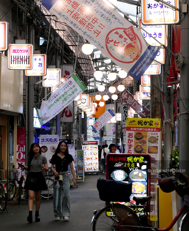 两个女孩在日本大阪的鹤桥市场漫步。图片素材