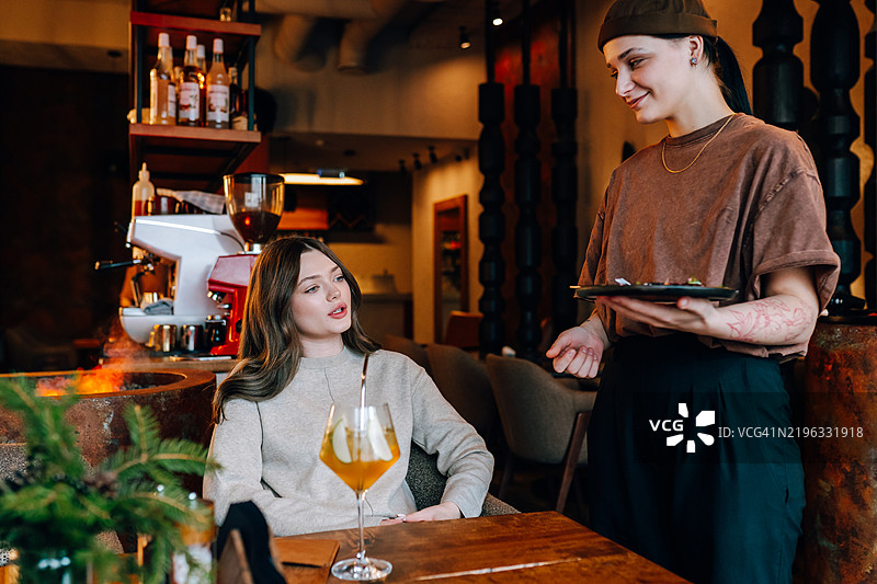 女服务员在餐厅为顾客上菜图片素材