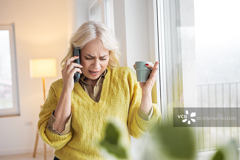 中年女性使用智能手机，面露愤怒之色图片素材