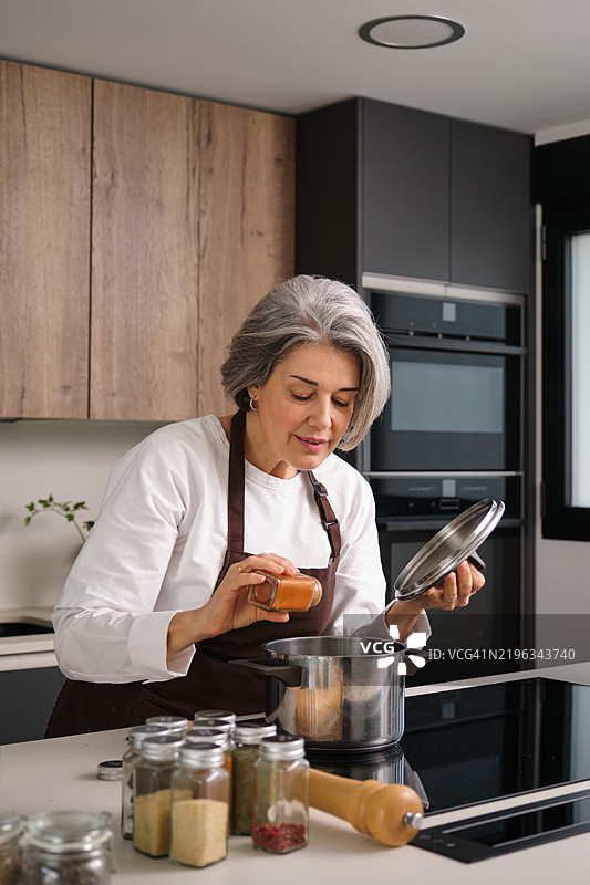 成熟的厨师在厨房里往锅里添加香料图片素材