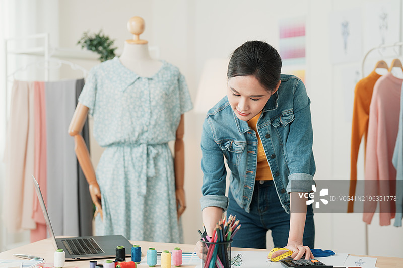 时装设计师在工作室中为模特素描创意并准备服装图片素材
