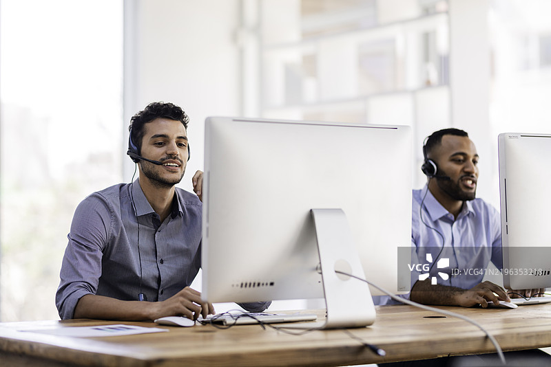 在办公室环境中使用耳机和电脑的客服人员图片素材