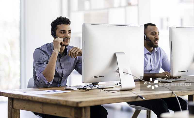 现代办公室环境中佩戴耳机的客户支持代表工作图片素材