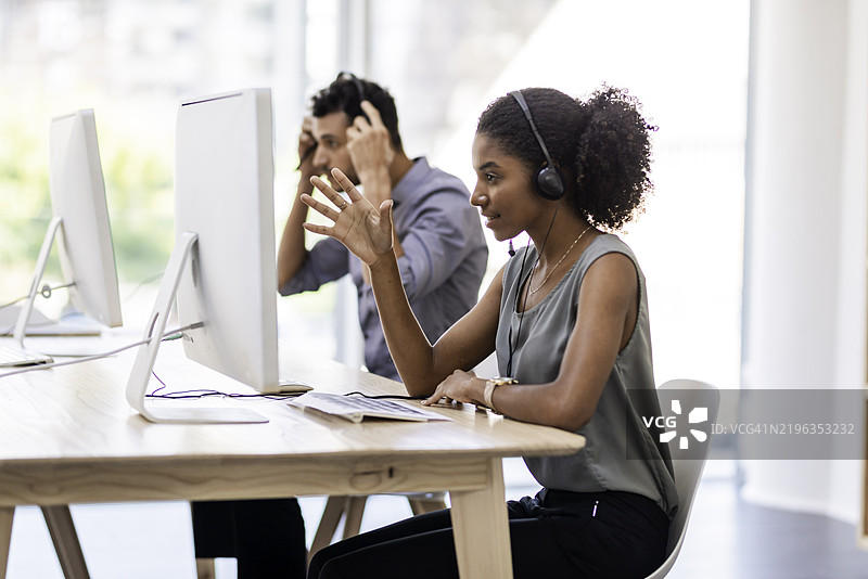 现代办公室中佩戴耳机的客户服务代表专注于工作图片素材