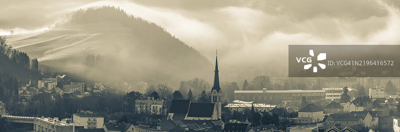 早晨的氛围和晨雾笼罩着加尔瓦里、瓦森教堂和老文法学校，背景是戈斯修道院，全景视图，莱奥本，施蒂利亚，奥地利，欧洲图片素材