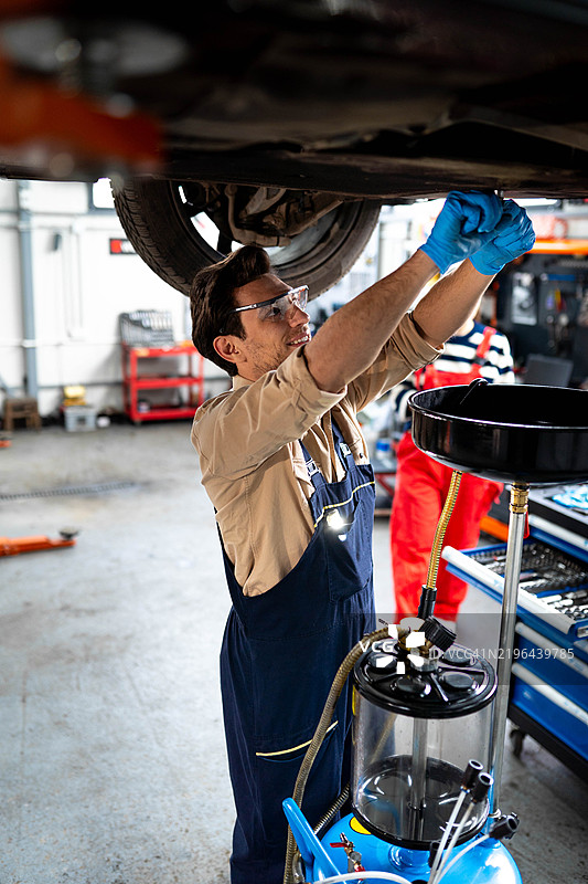 The mechanic is changing the oil.图片素材