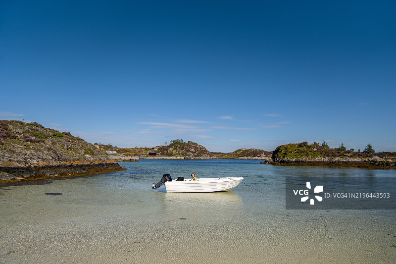 一个孩子在船上准备探索挪威奥斯特海姆的美丽沙滩Sauøyna。图片素材