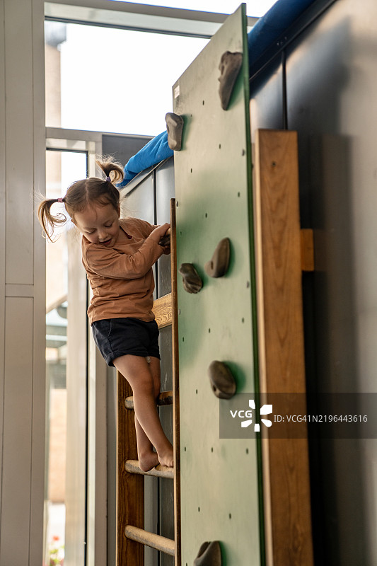 一个女孩在奥斯陆大学医院的室内游乐场爬梯子。图片素材