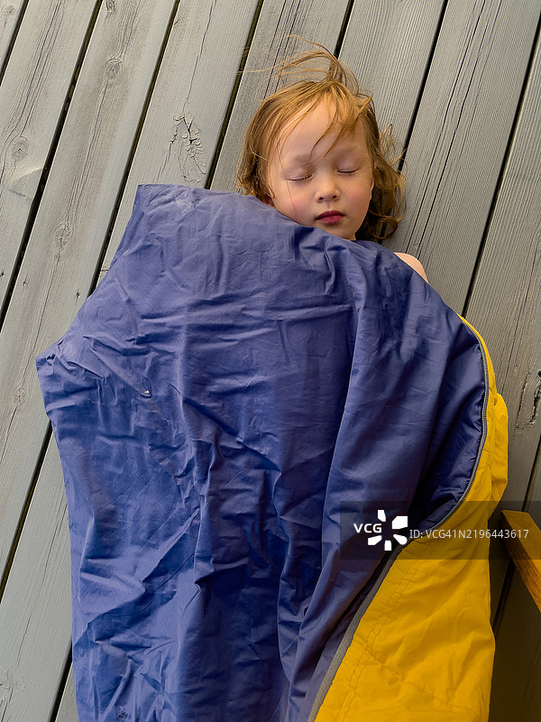 一个孩子在挪威奥斯特海姆的甲板上睡在睡袋里。图片素材