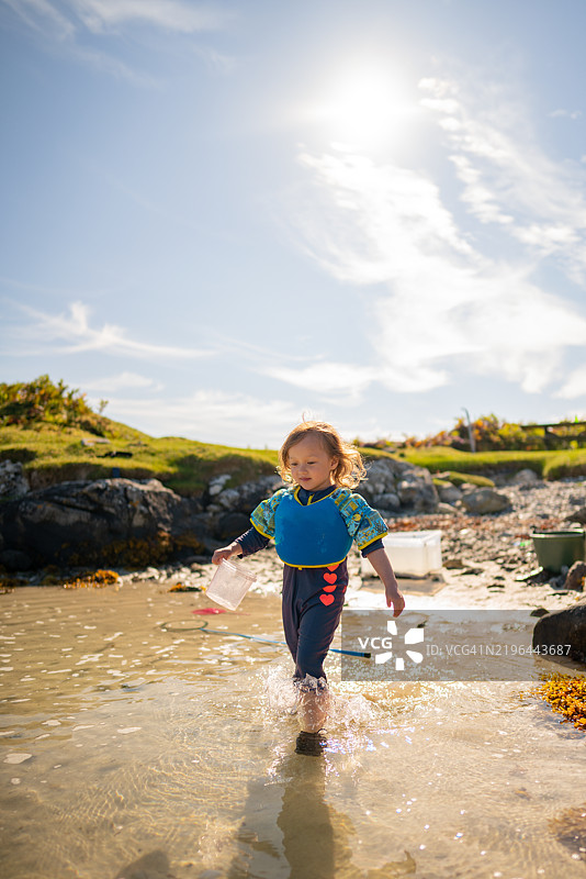 一个孩子在挪威奥斯特海姆的Sauøyna清澈的水面上行走。图片素材
