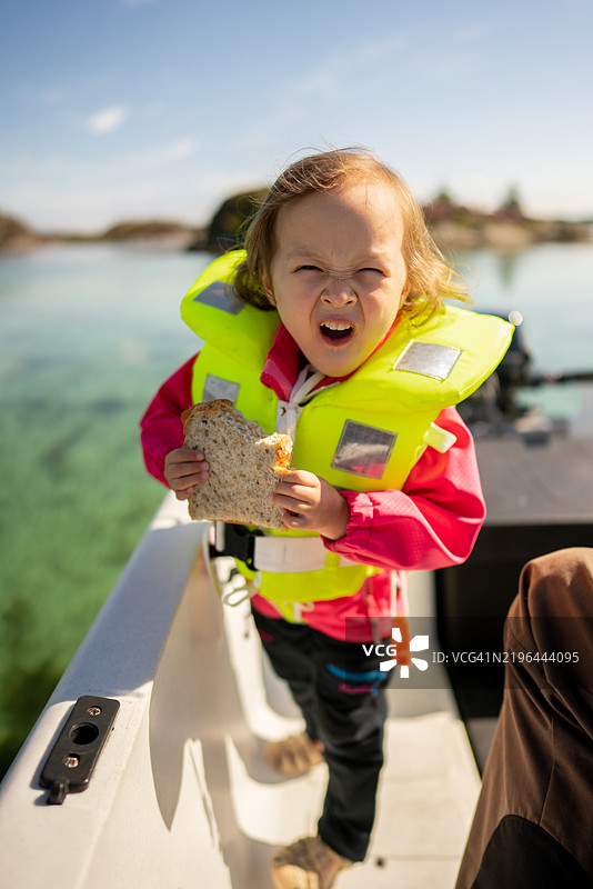 一个孩子在挪威奥斯特海姆的船上享受三明治。图片素材