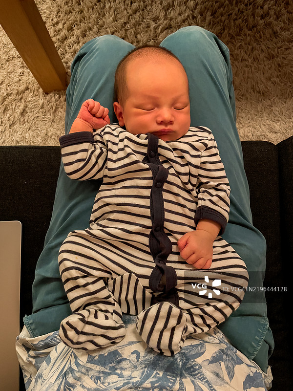 一个新生儿在一个人腿上睡觉。图片素材