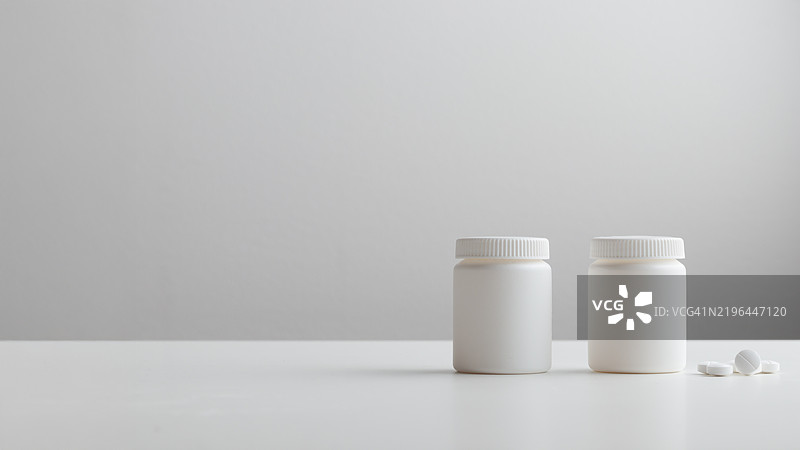 白色背景上的白色药丸和塑料药瓶，留有空白空间。医学和健康概念包括装有药丸或维生素的瓶子。高质量的照片横幅。图片素材