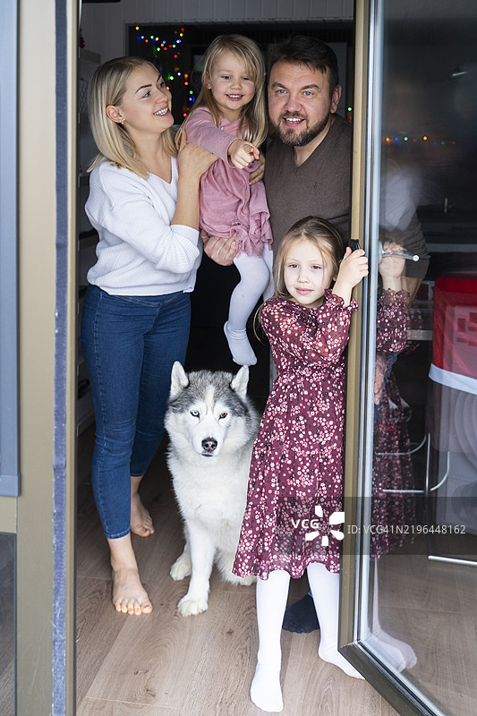快乐的家庭在家中与狗站在一起图片素材