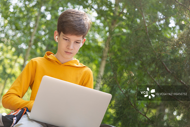年轻男孩在使用笔记本电脑进行网络交流图片素材