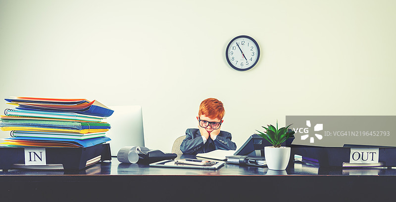 一位年轻男孩在桌子上用笔记本电脑工作，表情幽默且显得紧张和沮丧。图片素材