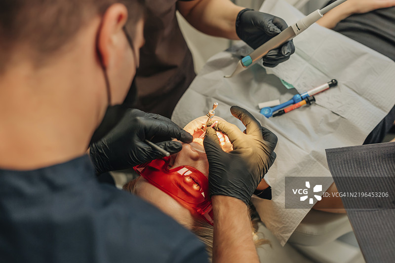 佩戴保护眼镜的女性正在接受牙科治疗图片素材