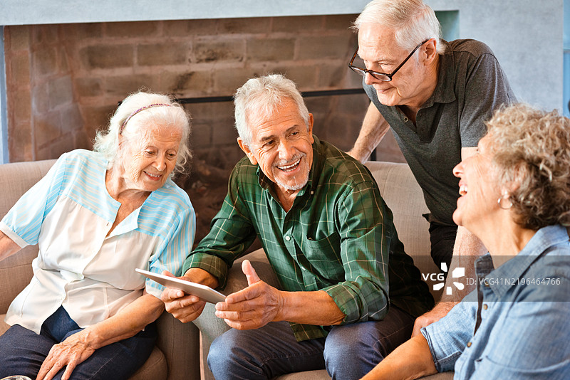 快乐的老年朋友们在家中使用平板电脑图片素材