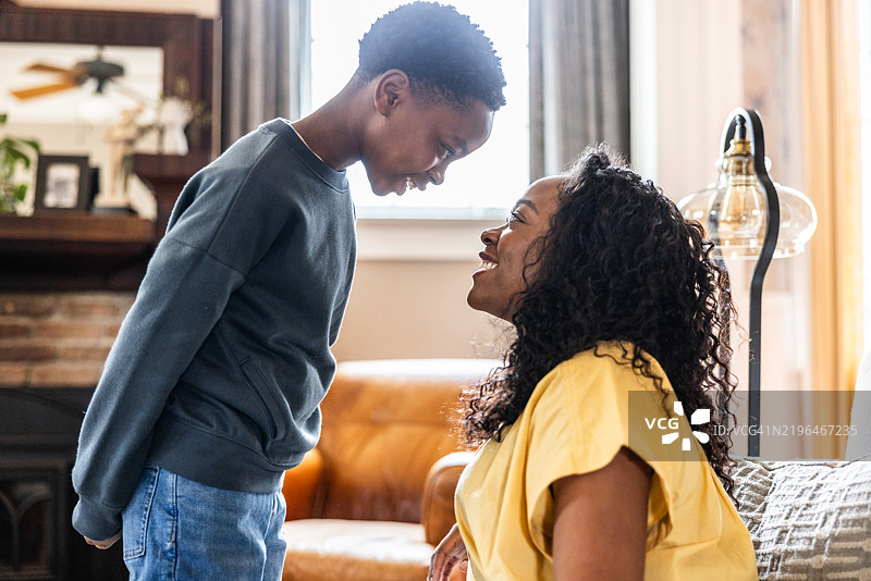 母亲和小儿子在客厅里对视并欢笑图片素材