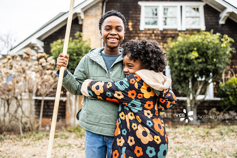 年轻的兄妹在郊区的院子里耙树叶图片素材