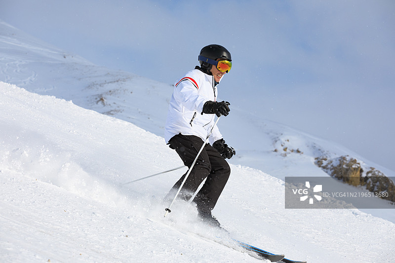蓝天上飘落着大雪花。活力四射的男士们在阳光明媚的滑雪胜地享受滑雪的乐趣。欧洲阿尔卑斯山的雪山，滑雪区域为瓦尔迪泽尔 - 蒂涅。图片素材