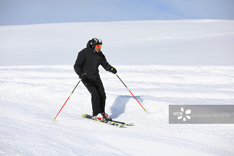 帅气的运动员在阳光明媚的滑雪胜地享受滑雪乐趣，背景是白雪皑皑的欧洲阿尔卑斯山。图片素材