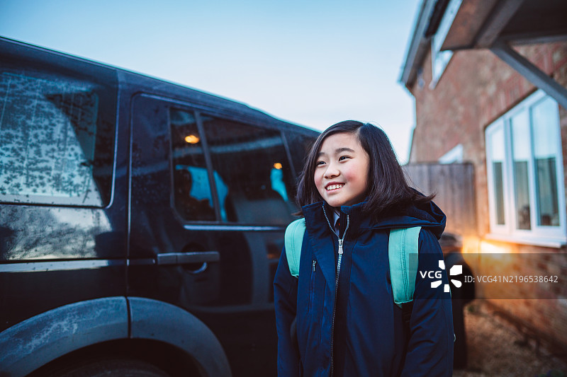 快乐的穿着校服的少女早晨离家，准备上车去学校。图片素材