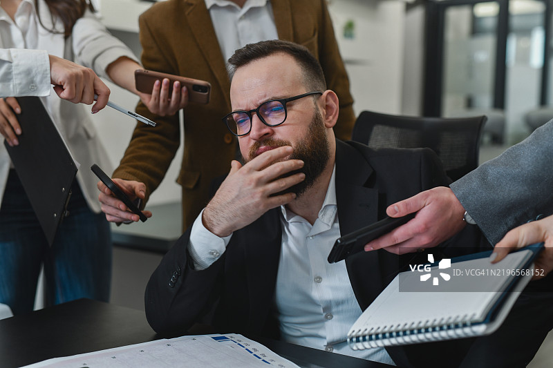 男性经理应对工作压力，被员工的问题压得喘不过气来图片素材