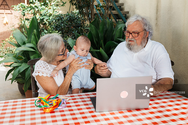 祖父母通过视频通话与家人见面，介绍他们的孙子。图片素材