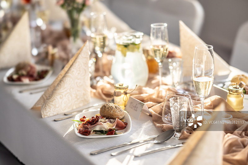 婚礼宾客准备的仪式性摆放的婚礼餐桌，上面有鲜花、香槟和开胃菜。图片素材
