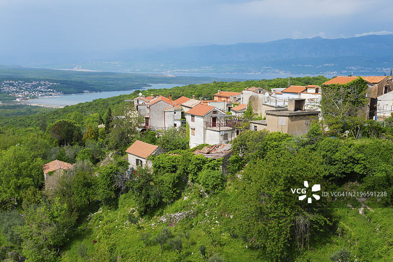 红屋顶的村庄景观，嵌入绿色植被中，背景是山脉，位于克尔克岛的多布林，克瓦尔内尔湾，普里莫里耶-戈尔斯基科塔尔，克罗地亚，欧洲图片素材