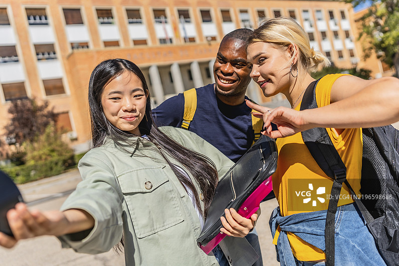 多民族大学生在校园里自拍，手指比出成功的手势图片素材